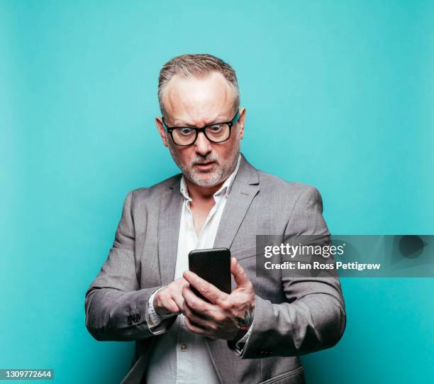 businessman making a face using smartphone - surprise portrait photos et images de collection