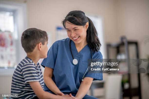 lächelnde asiatische ärztin mit einem kinderpatienten - nurse child stock-fotos und bilder