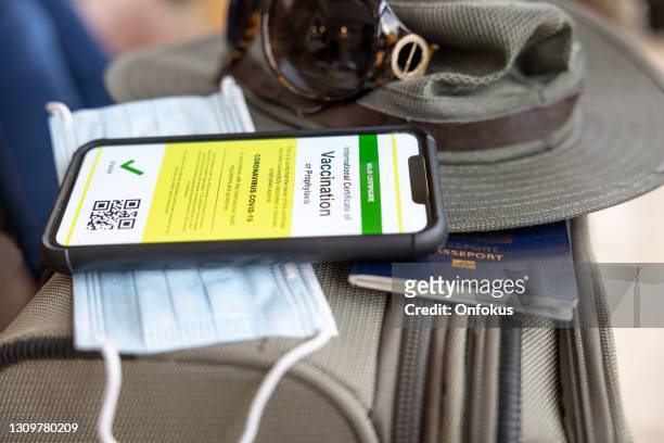 geimpfte frau mit digitalen impfstoff pass app im handy für reisen während covid-19 pandemie - canadian passport stock-fotos und bilder