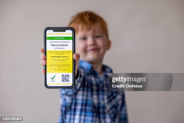 vaccinated boy using digital vaccine passport app in mobile phone at customs for travel during covid-19 pandemic - kids certificate stock pictures, royalty-free photos & images