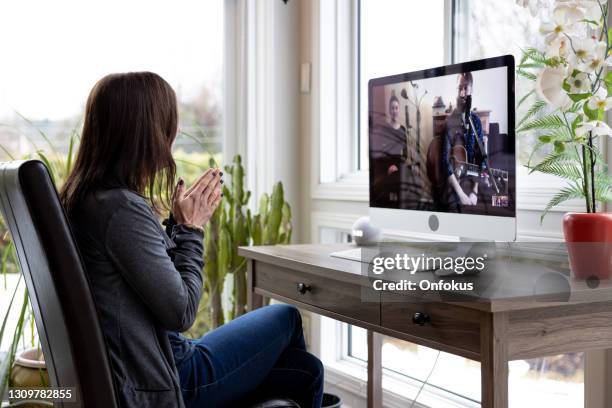 a woman is watching an online music concert from home for her birthday during covid-19 pandemic - live event covid stock pictures, royalty-free photos & images