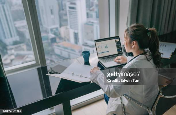 asian chinese female doctor working on medical report with laptop and document file - looking stock pictures, royalty-free photos & images