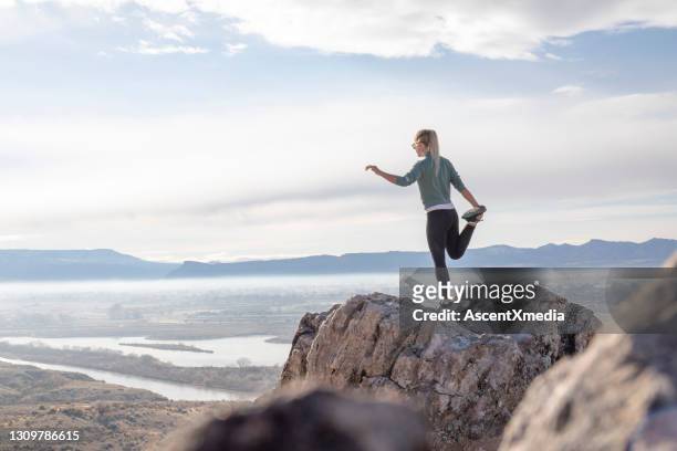 female trail runner stretches on mountain ridge in the morning - blonde yoga stock pictures, royalty-free photos & images