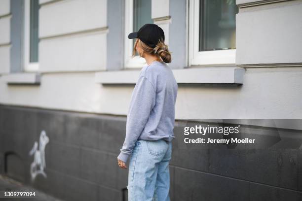 Michi Brandl wearing grey La Marel sweater, Zara blue jeans, Scholl Iconic clogs and Prada cap on March 25, 2021 in Cologne, Germany.