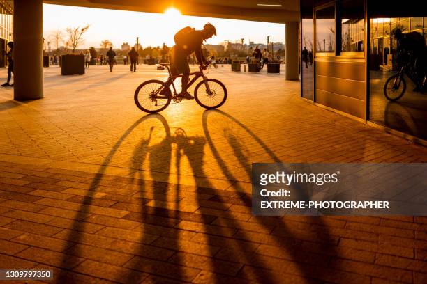 bike-stadtfahren bei sonnenuntergang - goldene stunde stock-fotos und bilder