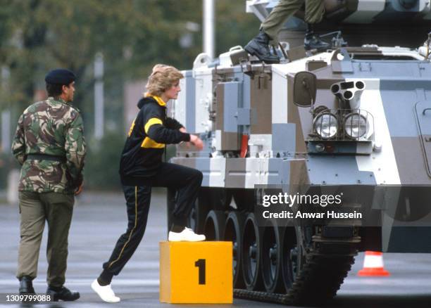 Diana, Princess of Wales, wearing a black and yellow regimental tracksuit and trainers, climbs inside a 15-ton tank to begin a driving lesson, as she...