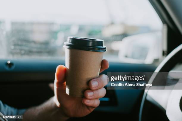 male hand with craft coffee in the car. disposable dishes, coffee on the road while driving. - coffee car design stock pictures, royalty-free photos & images