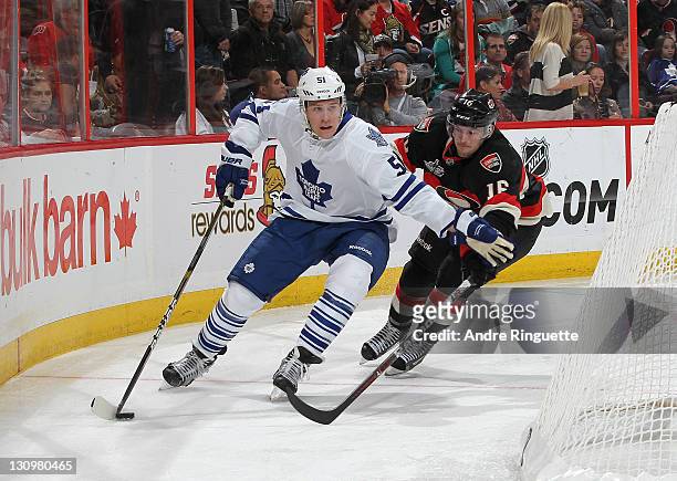 Jake Gardiner of the Toronto Maple Leafs skates the puck behind the net as Bobby Butler of the Ottawa Senators pressures on the forecheck at...