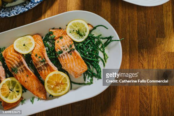 salmon on a serving plate on a table - fische und meeresfrüchte stock-fotos und bilder