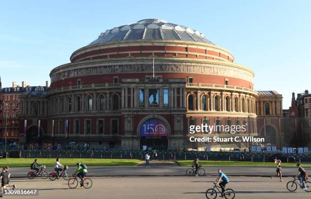 Cyclists ride by as the text "150 More History To Make" is displayed outside of the Royal Albert Hall on March 29, 2021 in London, England. Monday...