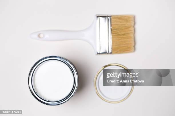 one clean paintbrush next to lid and metal bucket with white paint for renovation works on white background. flat lay style. copy space for your design. concept of redecoration in home interior. color swatch for design ideas - metal bucket stock pictures, royalty-free photos & images