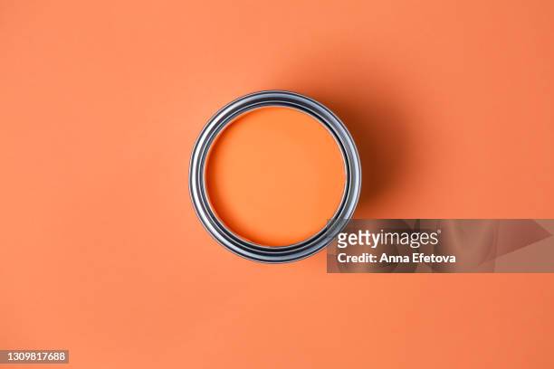 metal tin with bright orange paint for renovation works on orange coral peach background. flat lay style. copy space for your design. concept of redecoration in home interior. color swatch for design ideas - farbeimer stock-fotos und bilder