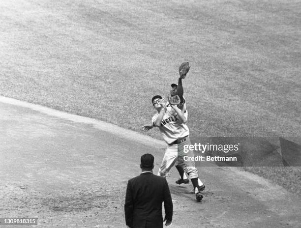 Los Angeles Angel's first baseman Vic Power outreaches second baseman Bobby Knoop to catch Yankees' Joe Pepitone's fly into short right field. The...