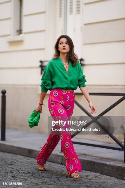 Alexandra Pereira wears colored necklaces, colored bracelets shaped as sea shells, a green shirt, a green woven leather bag from Bottega Veneta, bold...