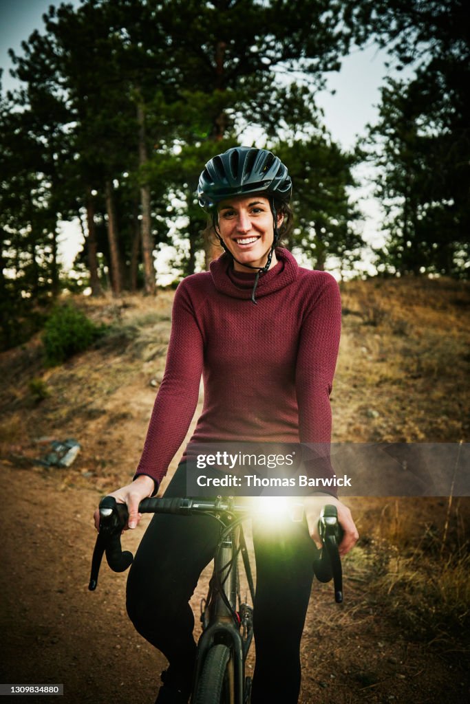 Portrait of smiling female athlete on nighttime gravel bike ride of forest road