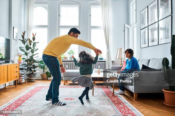 woman looking at girl dancing with her father - indian ethnicity family stock pictures, royalty-free photos & images