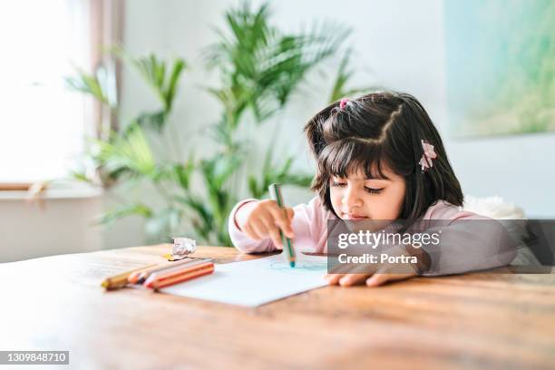 cute girl coloring with crayons at table - kid holding crayons stock pictures, royalty-free photos & images