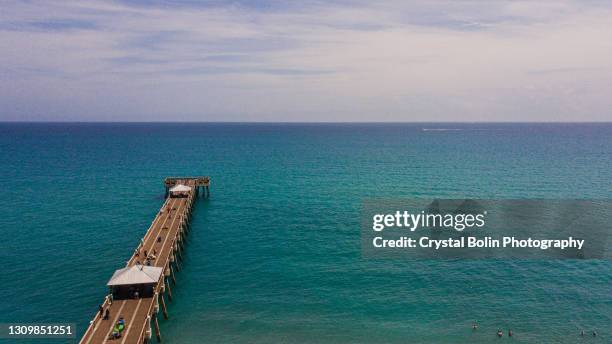 vista aerea del molo a juno beach, in florida, con acqua blu brillante dell'oceano a metà giornata durante le vacanze di primavera nel marzo del 2021 - jupiter florida foto e immagini stock