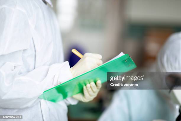 wearing protective workwear, holding note pad and writing observations - epidemiology stock pictures, royalty-free photos & images
