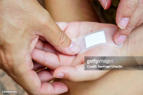 close-up of woman putting a band aid to a kid - hand laceration stockfoto's en -beelden