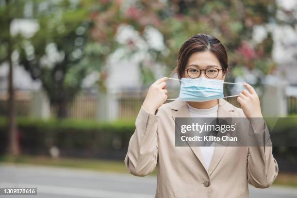 portrait of asian businesswoman putting on/removing face mask - removing surgical mask stock pictures, royalty-free photos & images