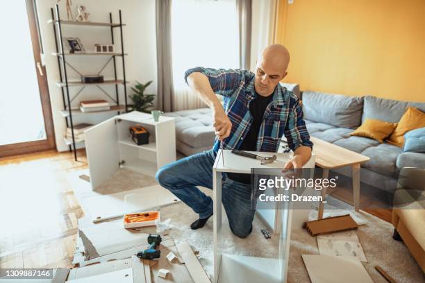 repairman working at home and assembling furniture during covid-19 lockdown - lockdown drill stock pictures, royalty-free photos & images