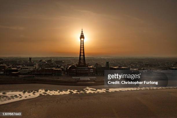 In an aerial view from a drone, the sun rises behind Blackpool Tower on March 30, 2021 in Blackpool, United Kingdom. Parts of the UK are set to see...