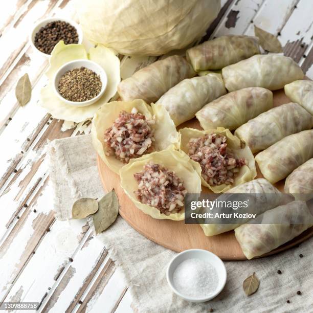 stuffed cabbage rolls with meat. cooking process. homemade preparations, minced meat and rice on cabbage leaves. raw convenience foods on kitchen table - cabbage roll stock pictures, royalty-free photos & images