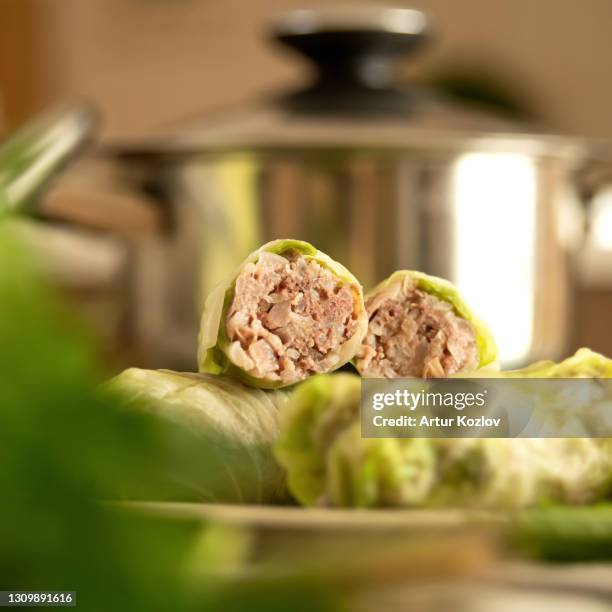 stuffed cabbage rolls with meat. raw or uncooked cabbage rolls cut in half. close up shot. metal pan on a blurred background. cooking process. soft focus - cabbage roll stock pictures, royalty-free photos & images