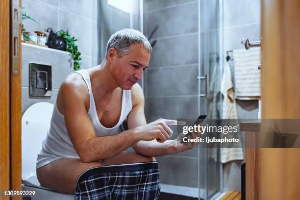 rijpe mensenlezing in het toilet - men taking a dump stockfoto's en -beelden