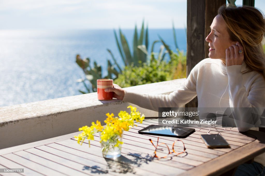 Woman working remotely on terrace overlooking the sea