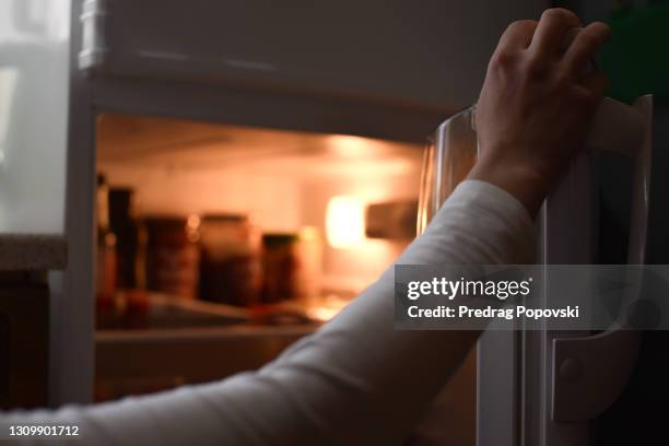 female hand opens fridge - frigorifero foto e immagini stock