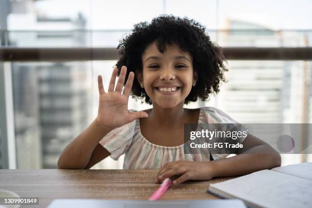 girl greeting to webcam on homeschooling during video call - looking to the camera imagens e fotografias de stock