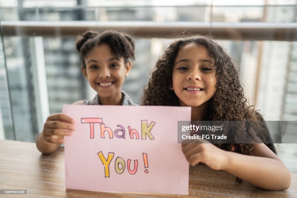 Porträt von Schwestern, die Papier mit "Danke" zu Hause geschrieben