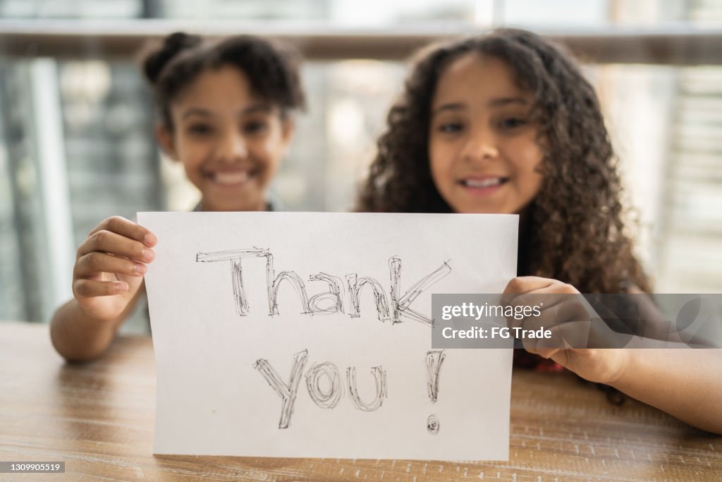 Porträt von Schwestern, die Papier mit "Danke" zu Hause geschrieben