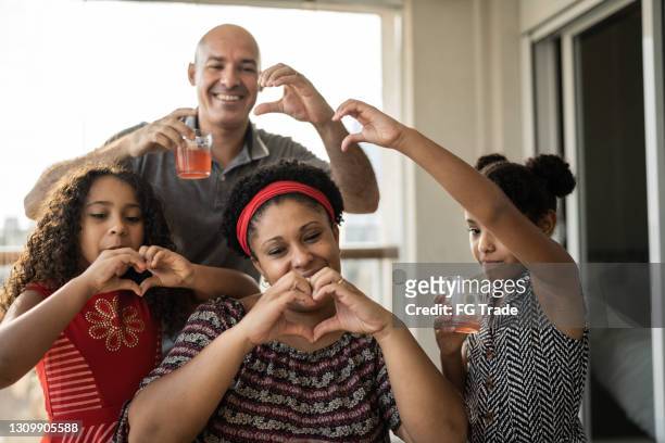 gelukkige familie die hartvorm met handen tijdens een videogesprek thuis doet - mother daughter webcam stockfoto's en -beelden