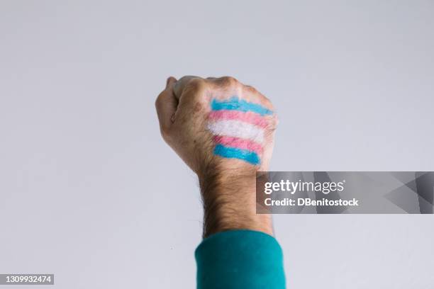 clenched fist of a man with a painted transsexual flag, wearing an lgtbiq flag bracelet - transgender bildbanksfoton och bilder