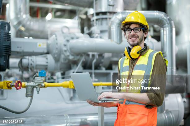service engineer working with laptop while examining industrial pipes and valve system in control room of factory. preventive maintenance concepts. - boiler engineer stockfoto's en -beelden