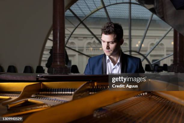 jeune homme de pianiste jouant le piano dans la salle de classe le soir - soliste photos et images de collection