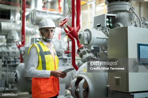 professional of service engineer working in boiler control room while using digital tablet to monitoring the operation of havc system ( heating, ventilation and air conditioning ) by mobile application. preventive maintenance concepts. - pomp stockfoto's en -beelden