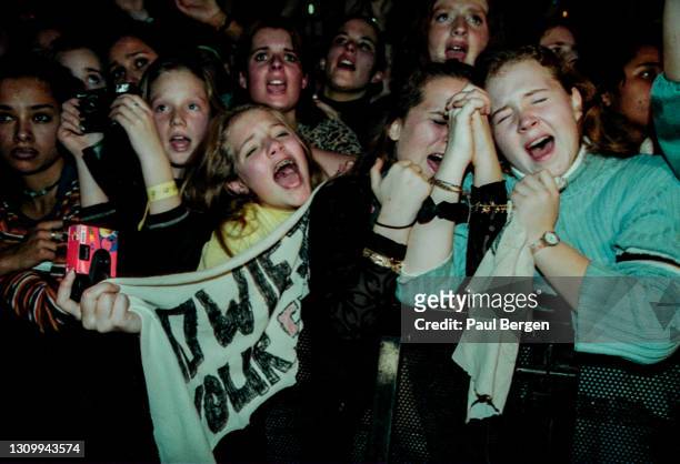 General view of emotional fans in the front rows of the audience, cheering, screaming and holding banners while watching American boyband Backstreet...