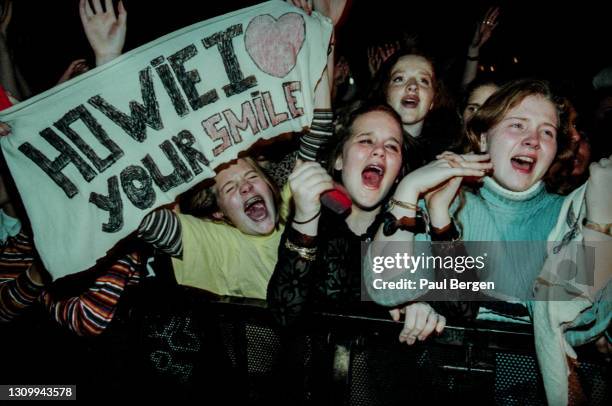 General view of emotional fans in the front rows of the audience, cheering, screaming and holding banners while watching American boyband Backstreet...