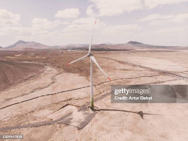 drone view of wind turbine in the desert landscape of fuerteventura island in sunny day. energia eolica a vista de dron en la isla de fuerteventura. spain. - energia eolica 個照片及圖片檔
