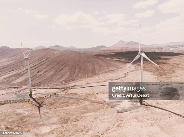 drone view of wind turbine in the desert landscape of fuerteventura island in sunny day. energia eolica a vista de dron en la isla de fuerteventura. spain. - energia eolica 個照片及圖片檔