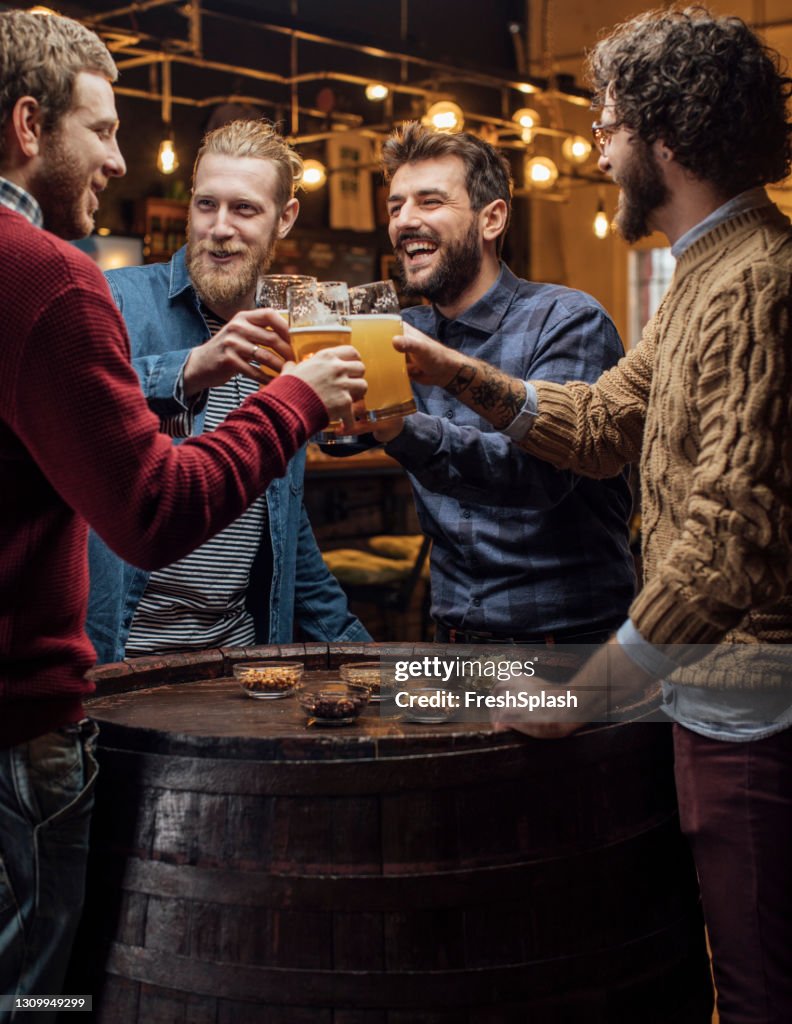 Group of Happy Men Drinking Beer at the Pub, Making a Toast