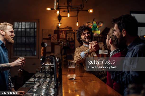 gruppe von freunden genießen ein paar bier in einer bar, lachen zusammen mit dem bartender - irish pub stock-fotos und bilder