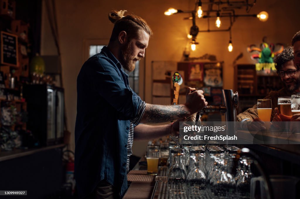 Side View of a Blond Bartender Pouring a Beer at the Bar
