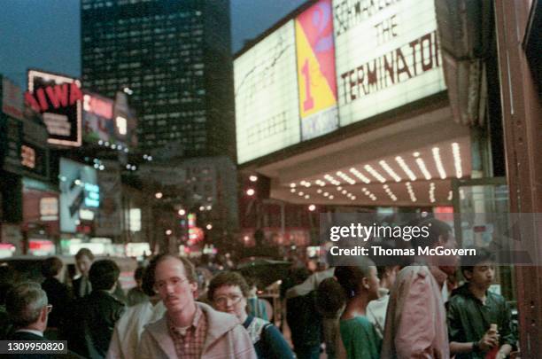 People in Times Square pass a cinema marquee featuring the film 'The Terminator', New York City, November 1st 1984.