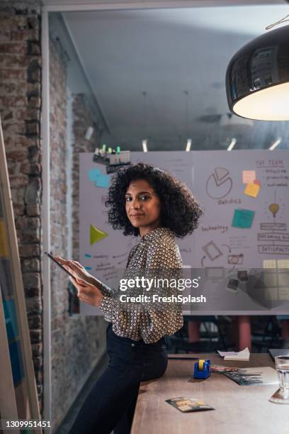 new normal concept: side view of a young african american young female entrepreneur holding files, alone at the office - design occupation stock pictures, royalty-free photos & images