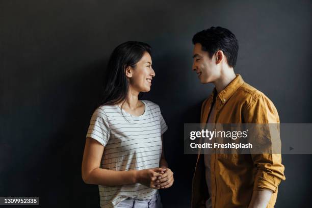 portrait of a cute asian couple standing against a dark grey background - couple dark background stock pictures, royalty-free photos & images